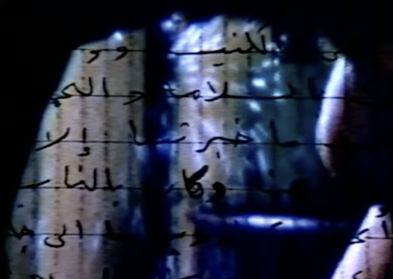Video still: blurred washes of black, purple and pink with handwritten Arabic script over them.